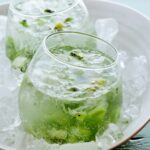 A close up of kiwi caipiroskas in a bowl of ice.