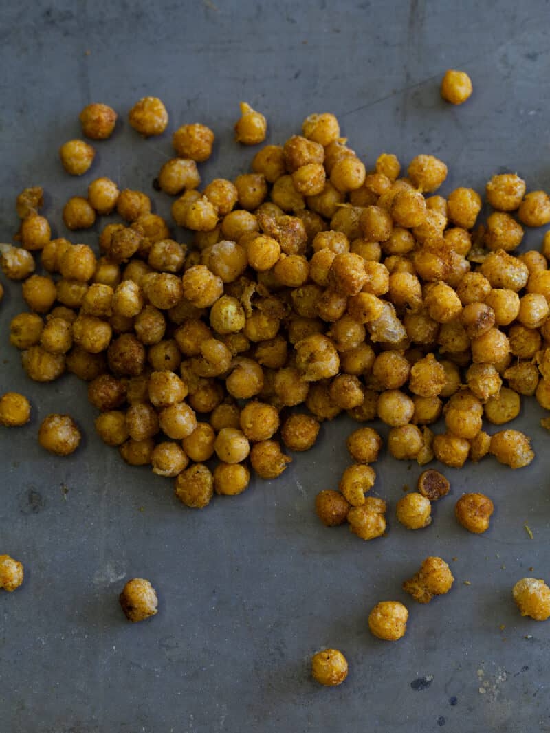 A close up of fried curry chickpeas on a dark surface.