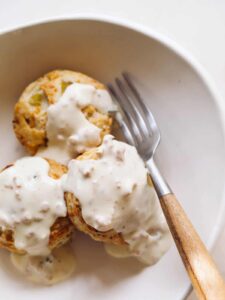A close up of green chili cheddar biscuits and gravy with a fork.