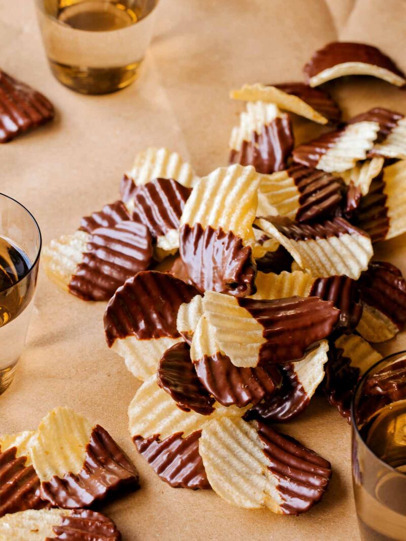 A table topped with chocolate covered potato chips with drinks.