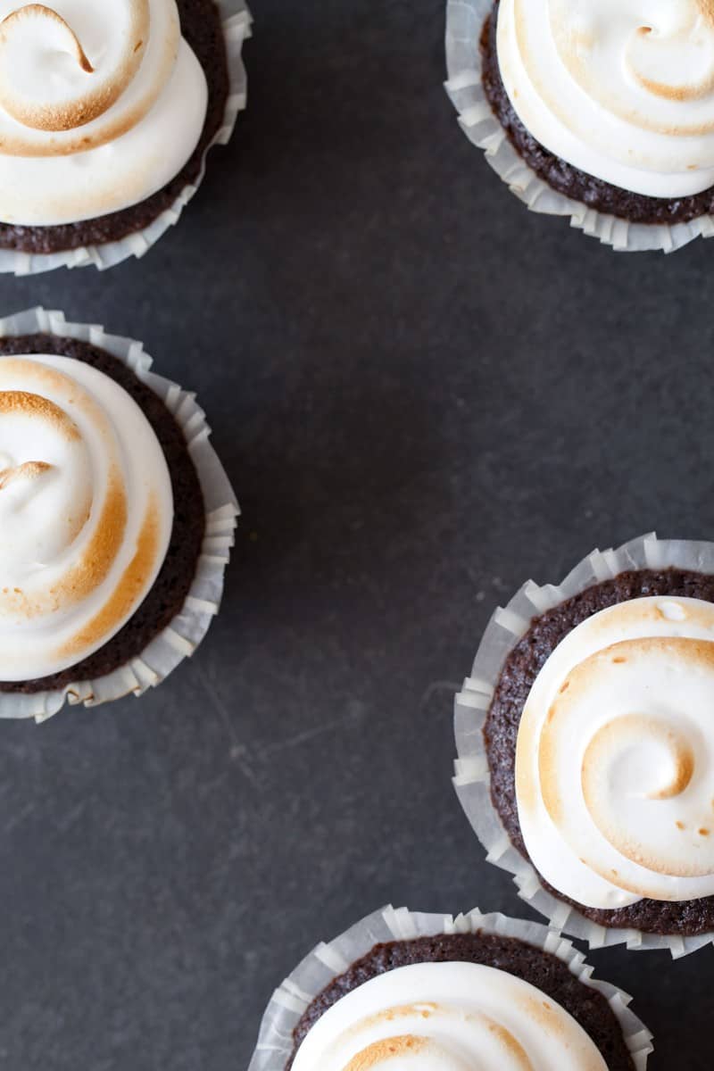 S’mores Cupcakes topped with a marshmallow frosting, graham crackers, and chocolate.
