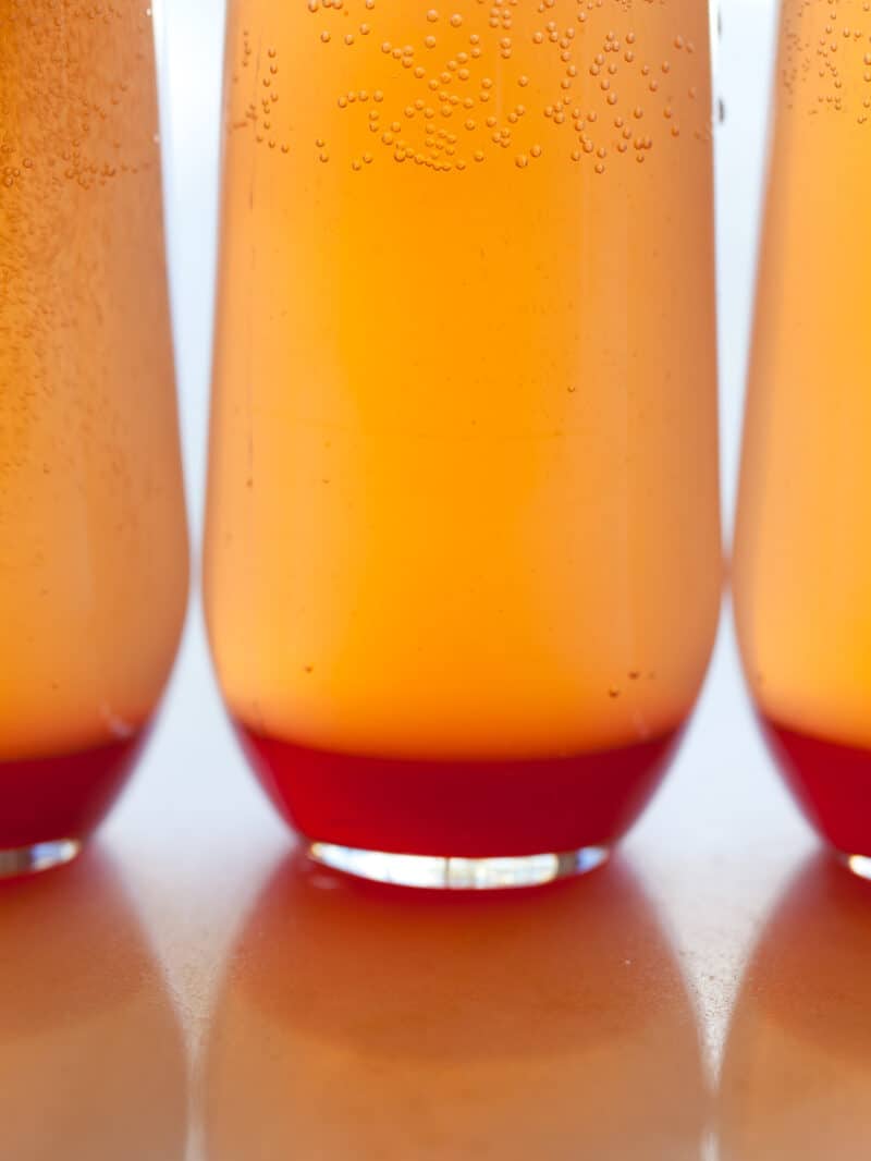 A close up of several glasses of spicy blood orange champagne punch.