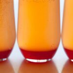 A close up of several spicy blood orange champagne punch in glasses.
