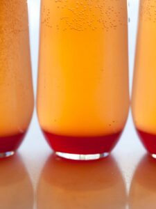 A close up of several spicy blood orange champagne punch in glasses.