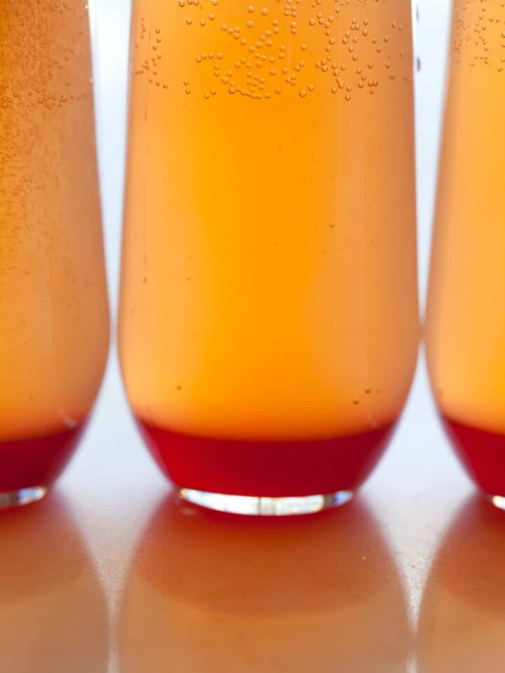 A close up of several spicy blood orange champagne punch in glasses.