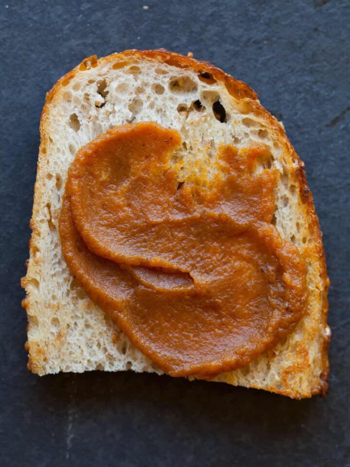 A close up of a piece of bread with sweet pumpkin butter spread on top.