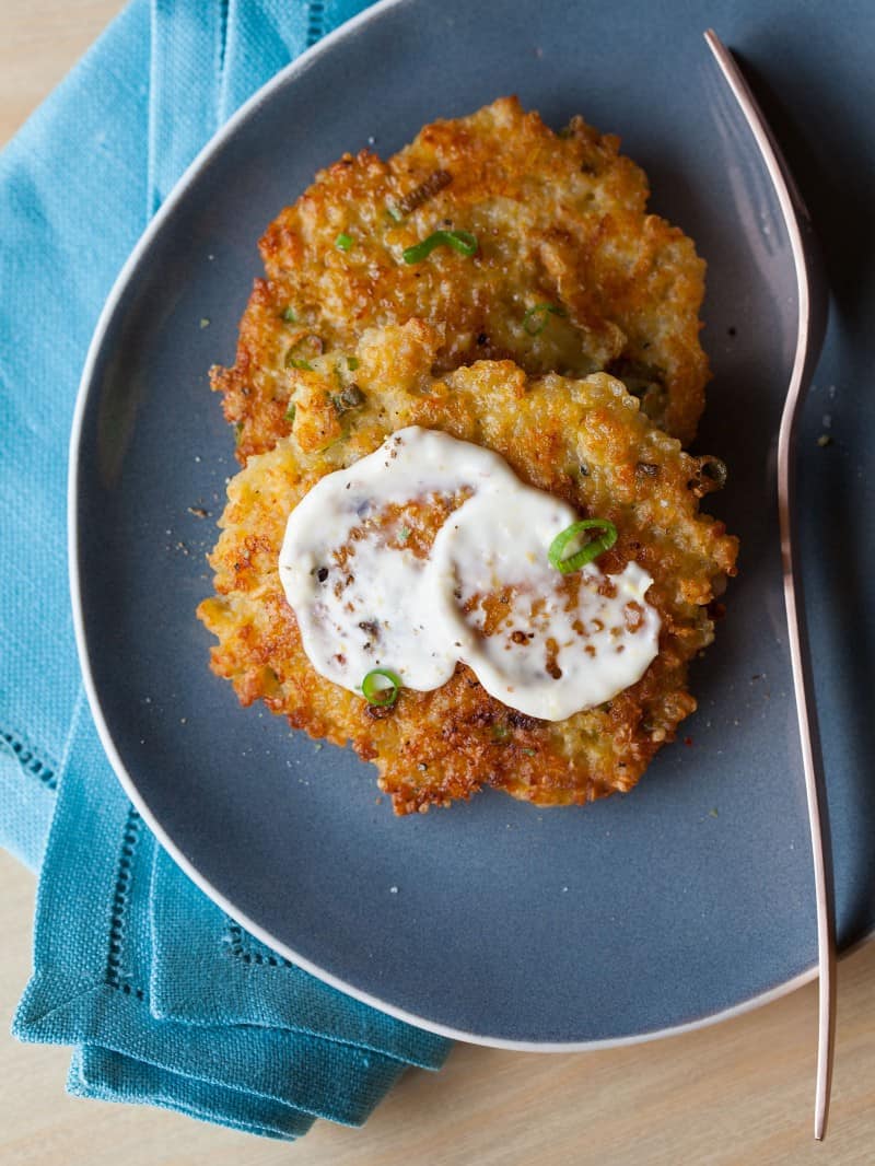 A plate of cheesy quinoa cakes with roasted garlic and lemon aoli, a fork and napkin.