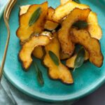 Maple glazed roasted acorn squash on a turquoise plate with a fork.
