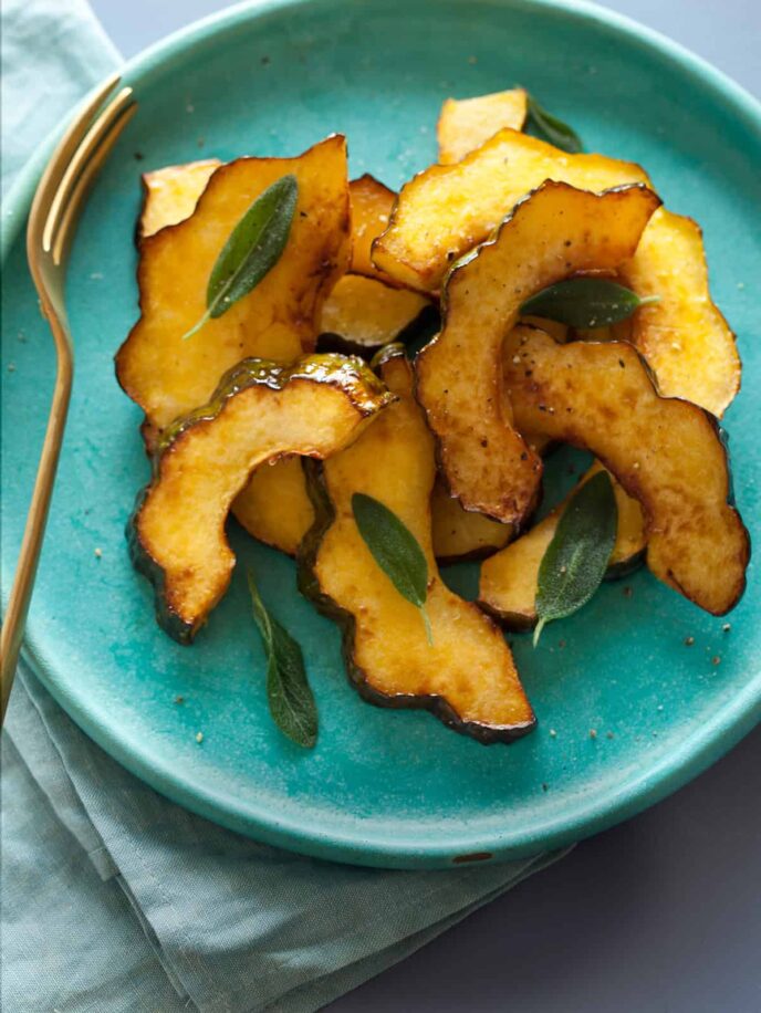 Maple glazed roasted acorn squash on a turquoise plate with a fork.