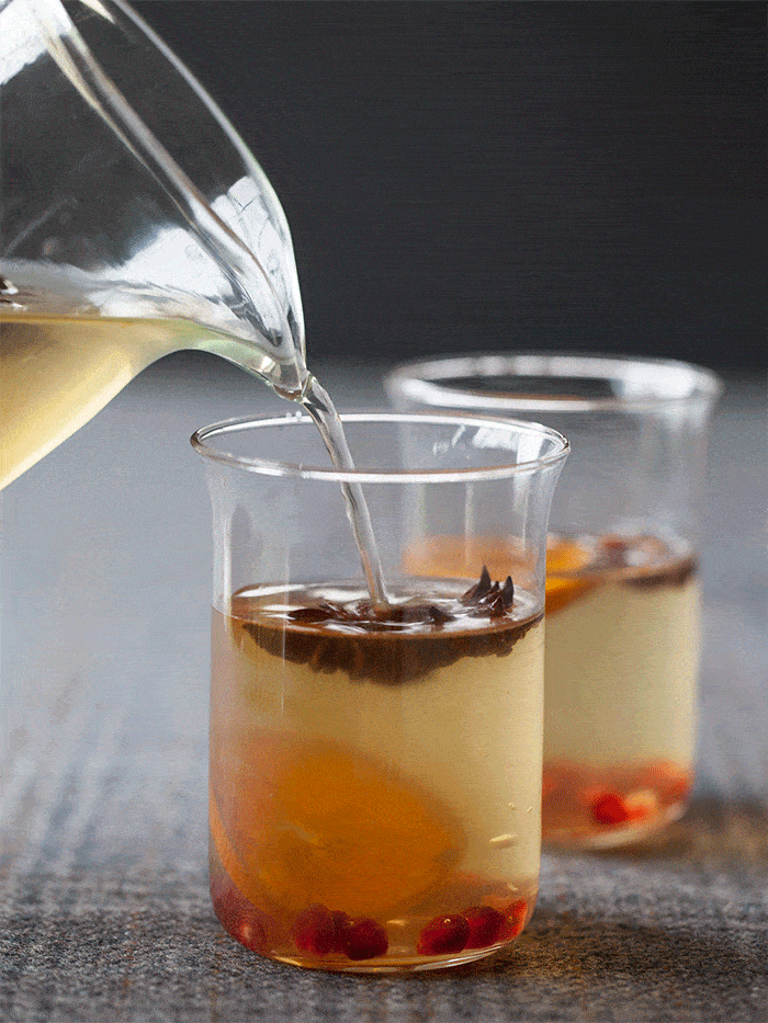 Close up of glasses of spiced white wine sangria being poured from a glass pitcher gif.