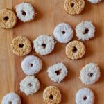 No yeast cake doughnuts with a variety of toppings on a wooden countertop.