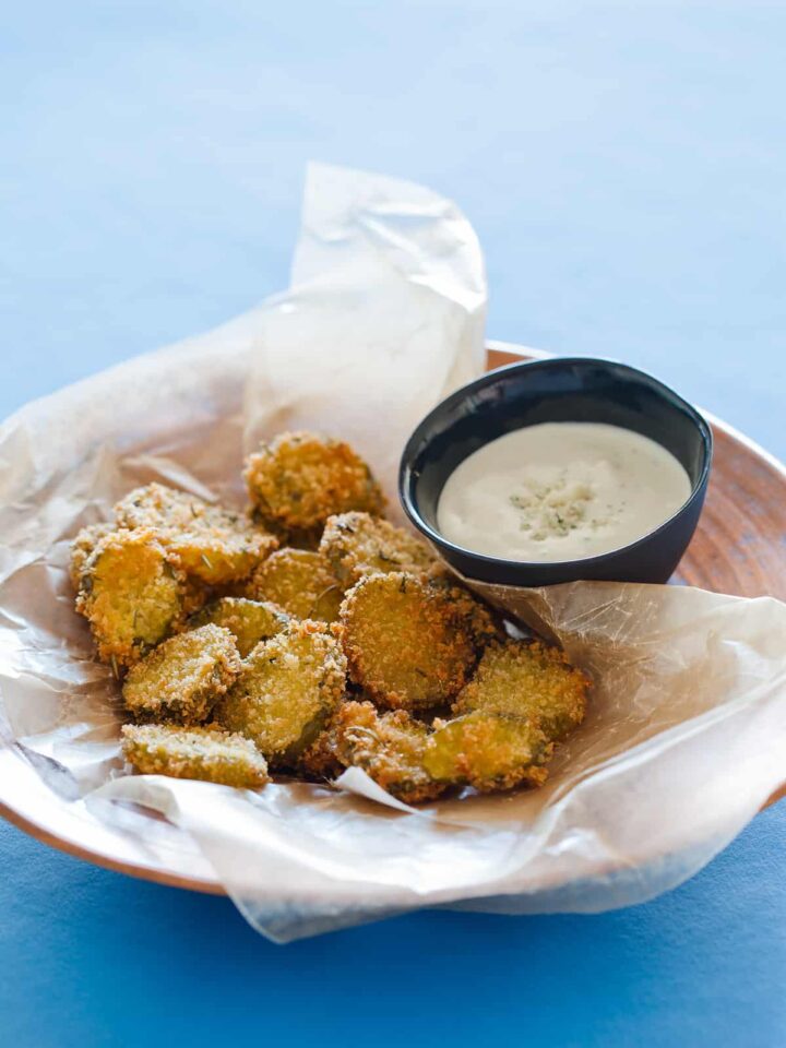 A plate of fried pickle chips and a small bowl of bleu cheese dipping sauce.