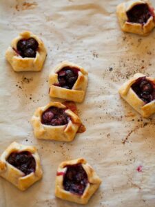A close up of mini blueberry galettes on parchment paper.