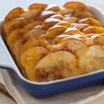 Baked apple french toast in a blue baking dish on a napkin.