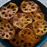 A close up of cumin spiced baked lotus chips in a blue bowl.