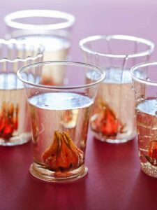 A close up of glasses of hibiscus ginger champagne cocktails.