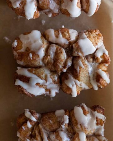 A close up of a piece of cinnamon sugar messy bread with vanilla icing.