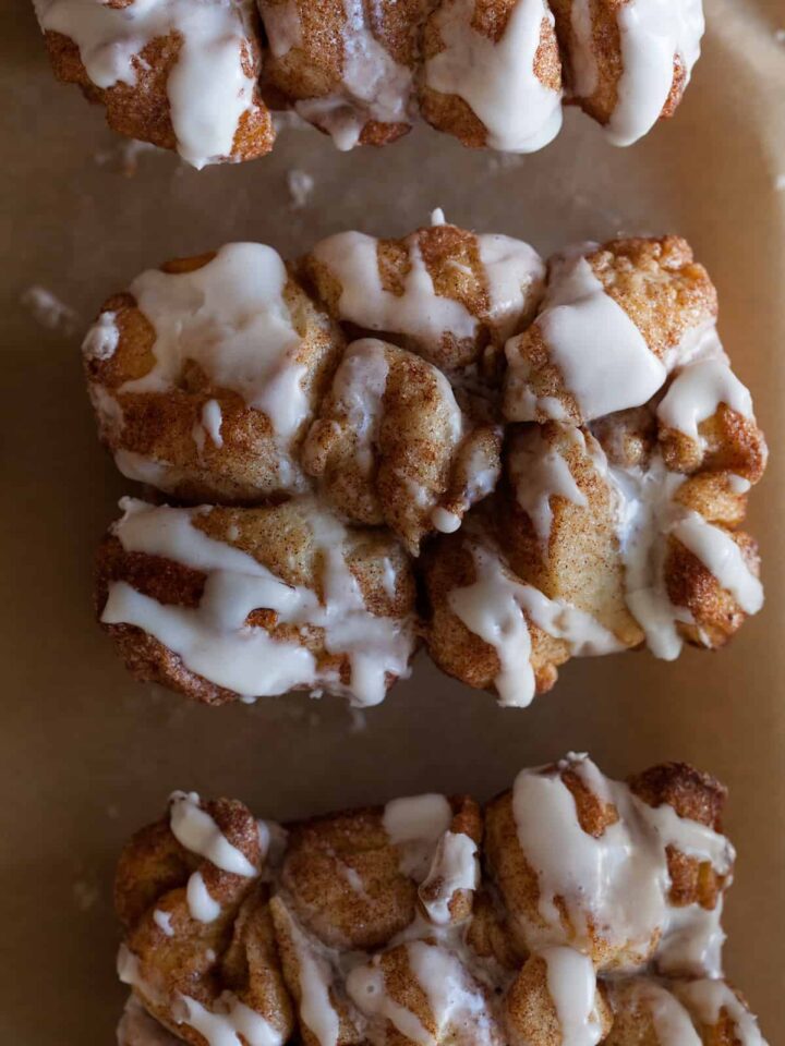 A close up of a piece of cinnamon sugar messy bread with vanilla icing.