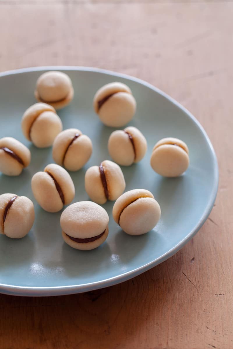 A plate of baci di dama on a wooden surface.