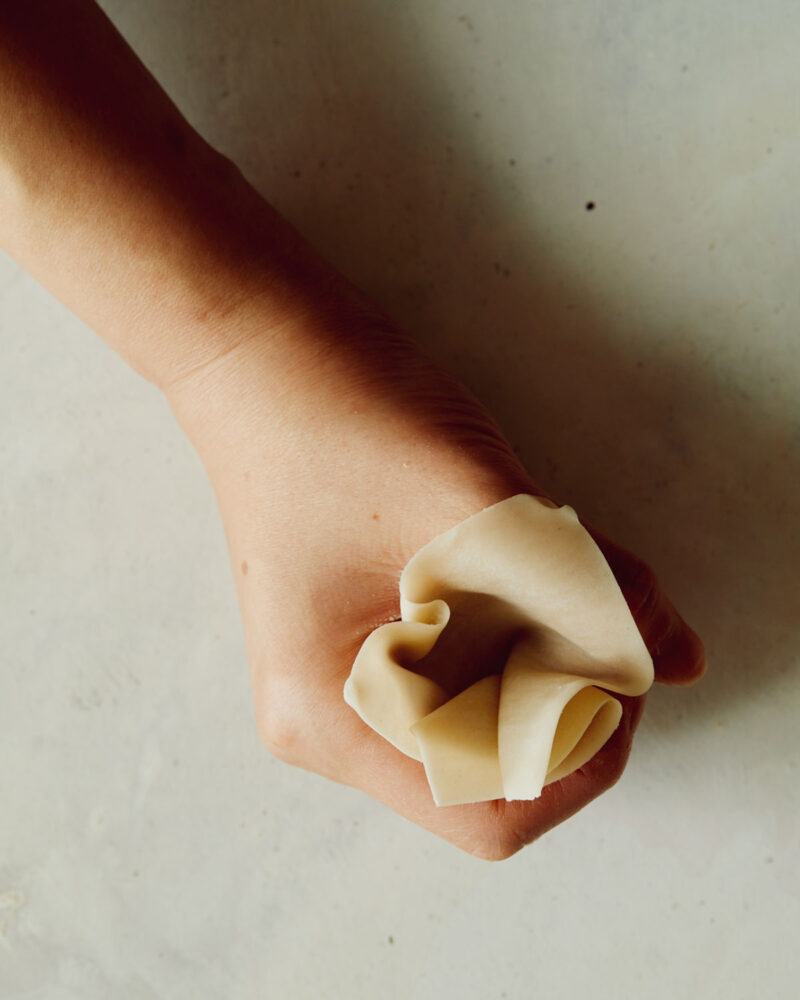 Step 3 of forming shrimp shumai. The cavity should be deep enough to hold about half a tablespoon of the shrimp mixture inside. The edges of the wonton wrapper that lay on top of your hand will be folded down later. Be sure to not make your cavity too deep, that will just leave your edges messy. 