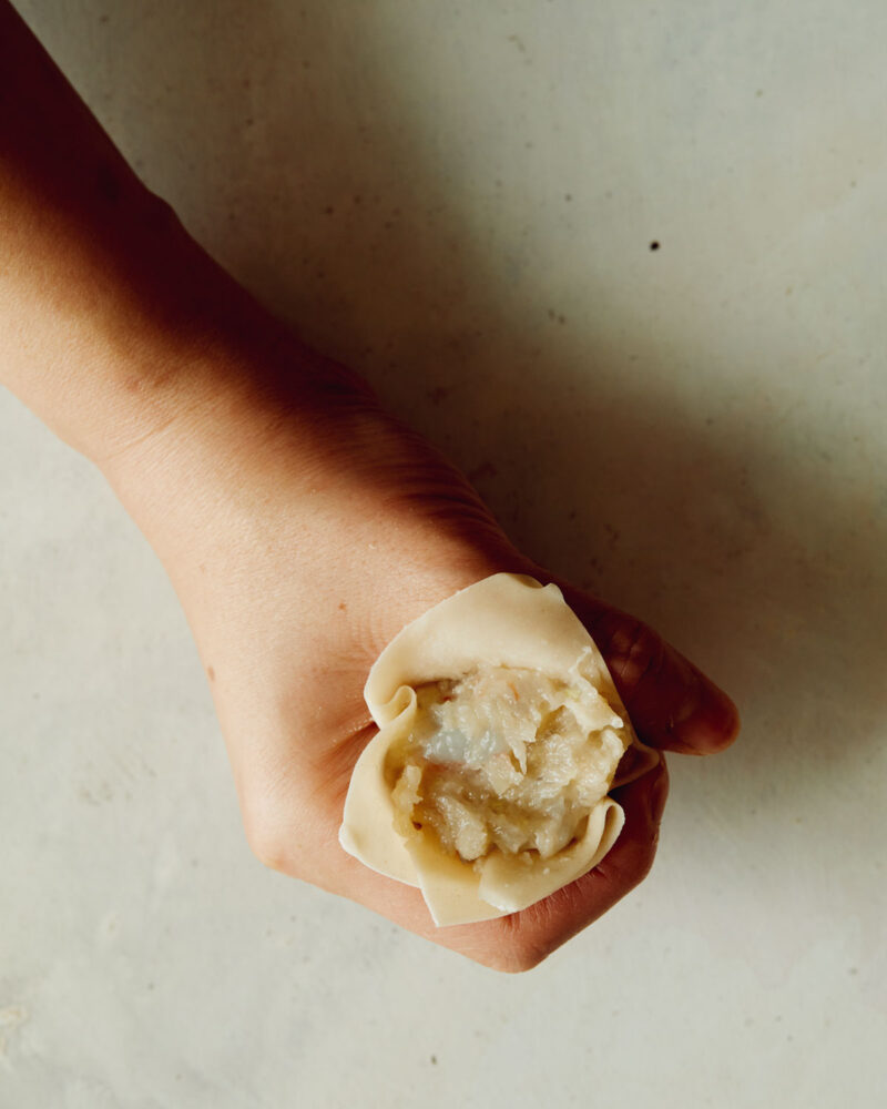 Step 4 of making shrimp shumai. Using a spoon, place the shrimp mixture in the cavity. We like to use a gently scraping method when we do this. You can use the spoon to gently pack the mixture down and create a clean top.