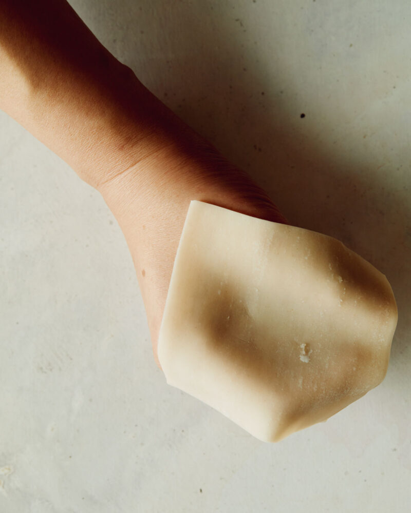 Raw wonton wrapper placed on hand making a fist.