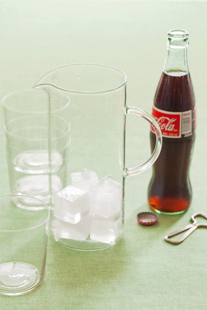 A bottle of wine and then a bottle of coke being poored into a glass pitcher gif.