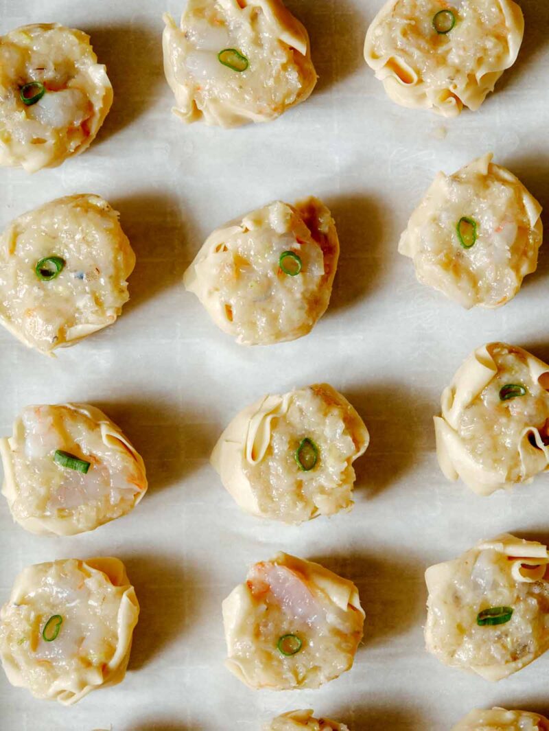 overhead of 12 raw shrimp shumai on parchment paper