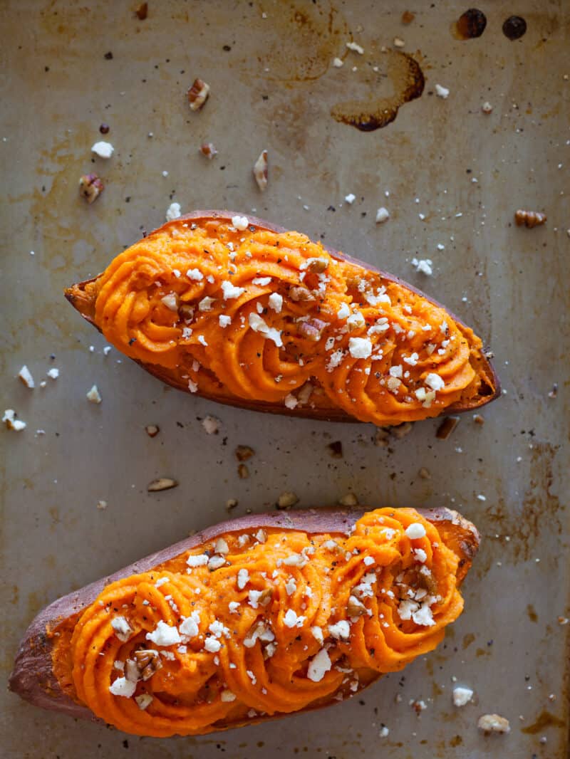 Twice baked sweet potatoes on a sheet pan with chopped pecans and feta.