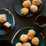 Several small plates of bunuelos with spicy chocolate sauce on some and on the side.