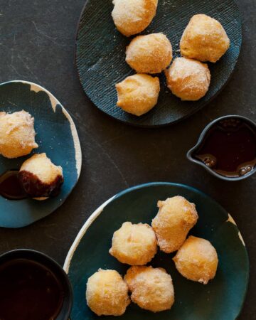 Several small plates of bunuelos with spicy chocolate sauce on some and on the side.