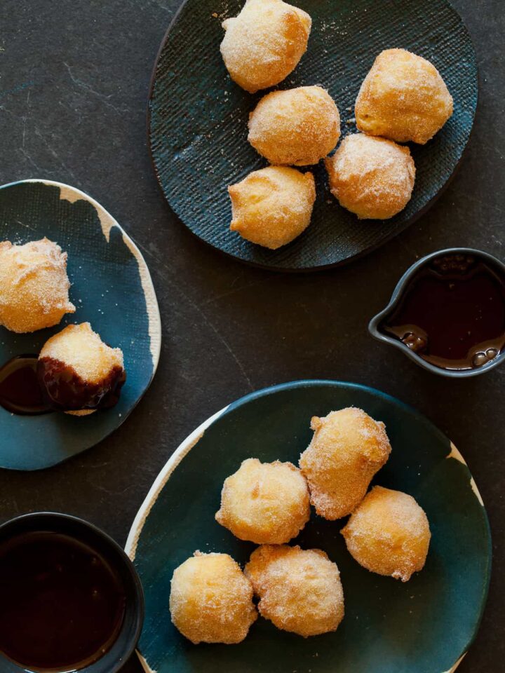 Several small plates of bunuelos with spicy chocolate sauce on some and on the side.