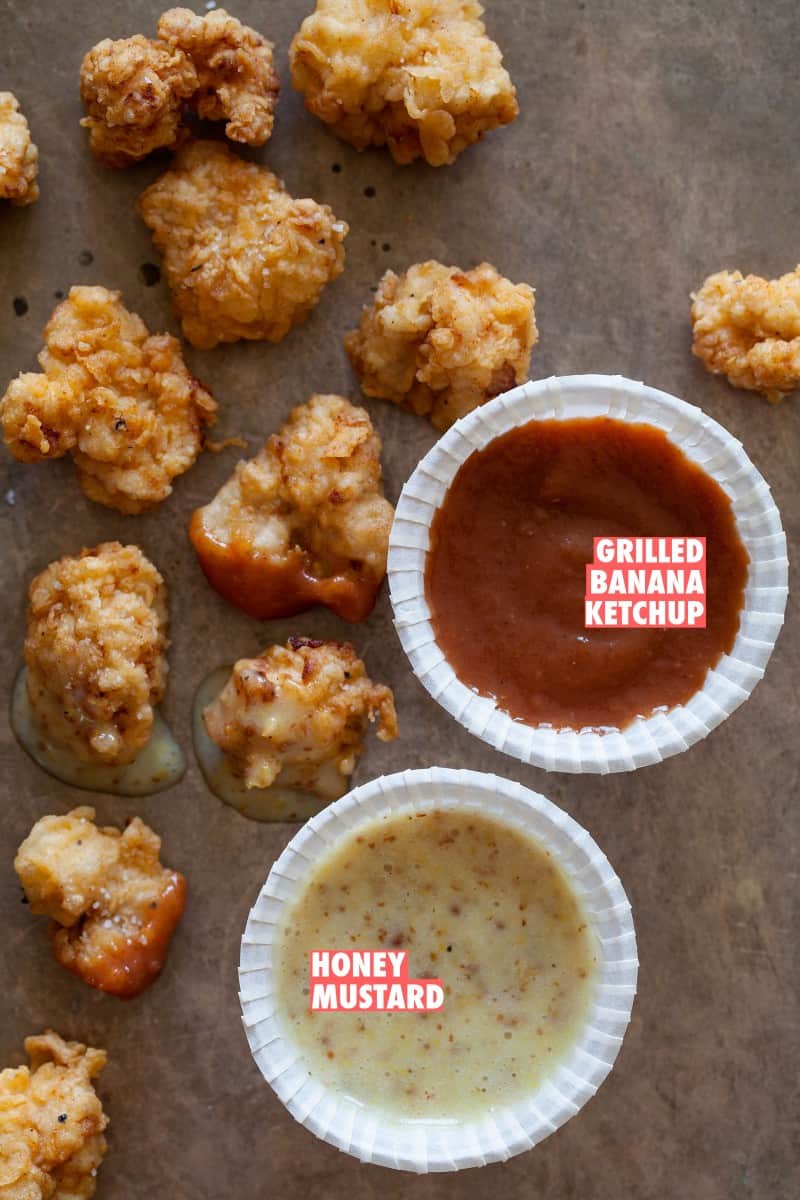 A close up of sweetbread nuggets with grilled banana ketchup and honey mustard dipping sauces.