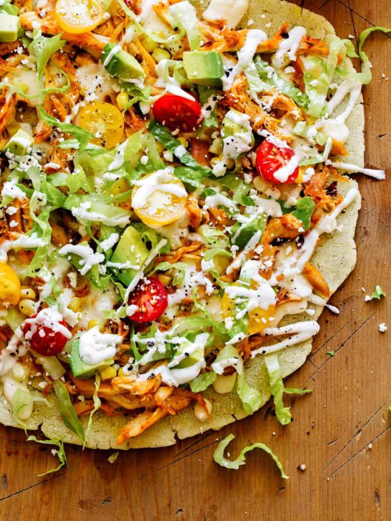 A close up of an arepa pizza with chipotle chicken and cilantro yogurt sauce.