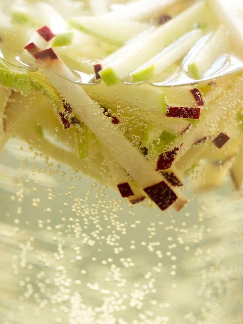 A close up of julienned apples in sparkling apple sangria.