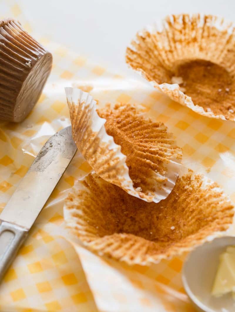 A close up of empty muffin liners with a butter knife.