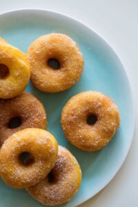 A close up of a plate of sweet potato spudnuts coated with sugar and cinnamon.