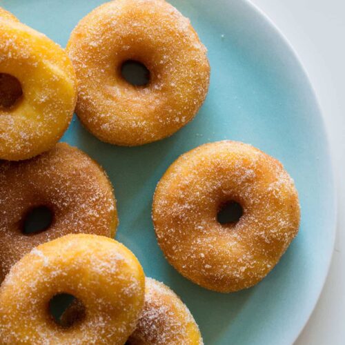 A close up of a plate of sweet potato spudnuts coated with sugar and cinnamon.