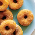 A close up of a plate of sweet potato spudnuts coated with sugar and cinnamon.