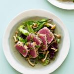 A bowl of black sesame and almond crusted ahi tuna on mixed greens with beech mushrooms.