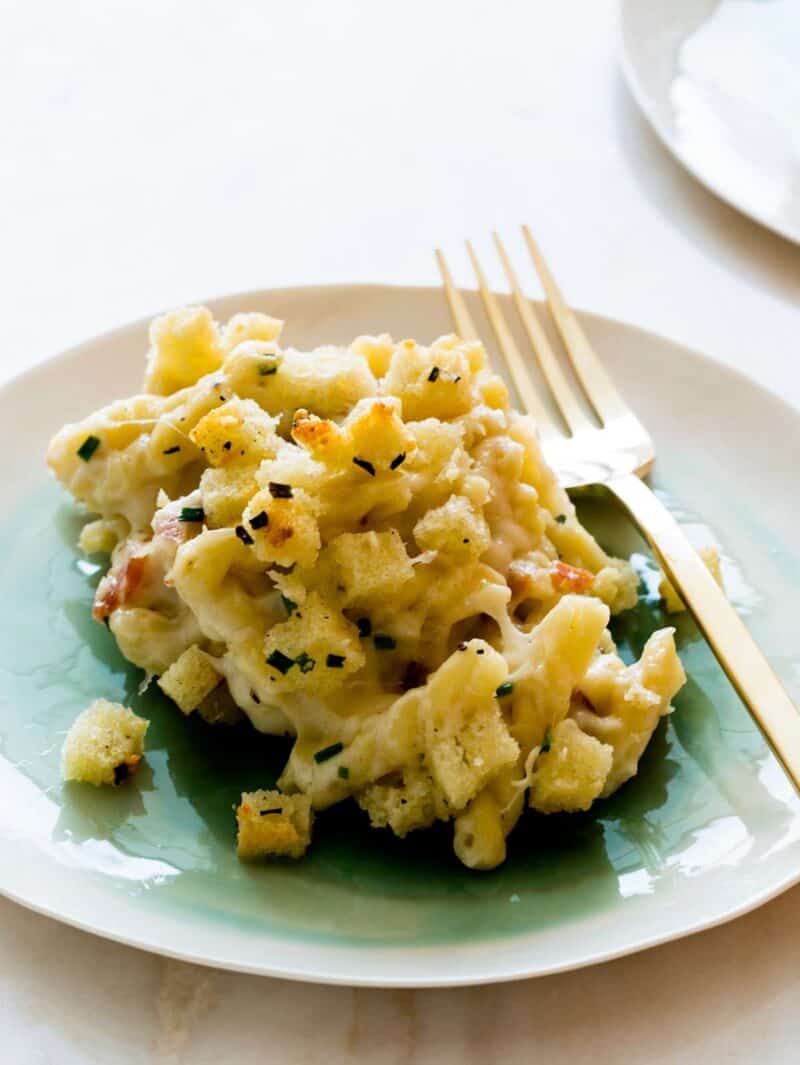 A close up of five cheese baked mac and cheese on a plate with a fork.