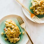 Five cheese baked mac and cheese on plates with forks.