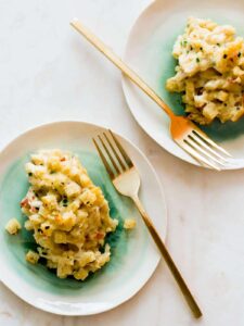 Five cheese baked mac and cheese on plates with forks.