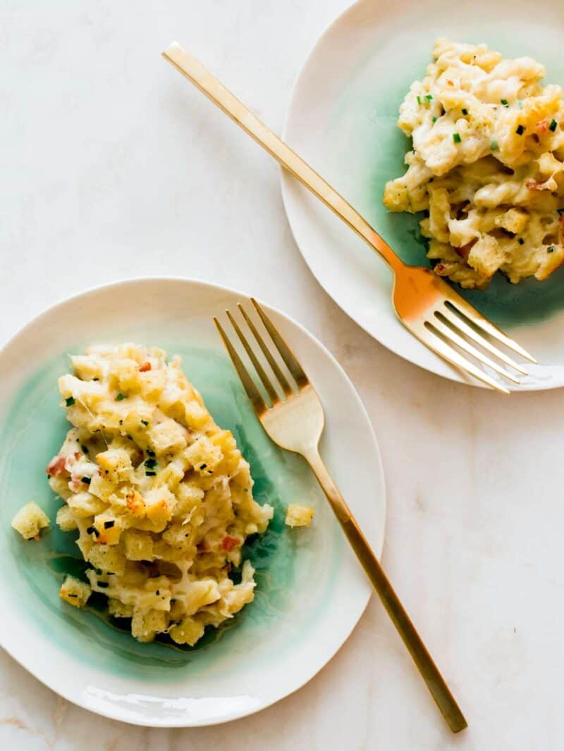 Five cheese baked mac and cheese on plates with forks.