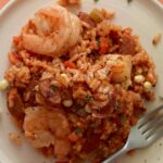 A close up of shrimp and andouille jambalaya with a fork.