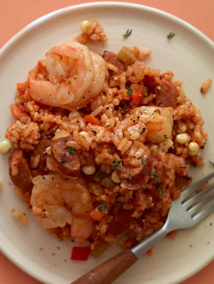 A close up of shrimp and andouille jambalaya with a fork.