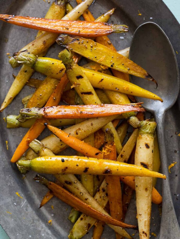 A plate of balsamic grilled baby carrots with a spoon.