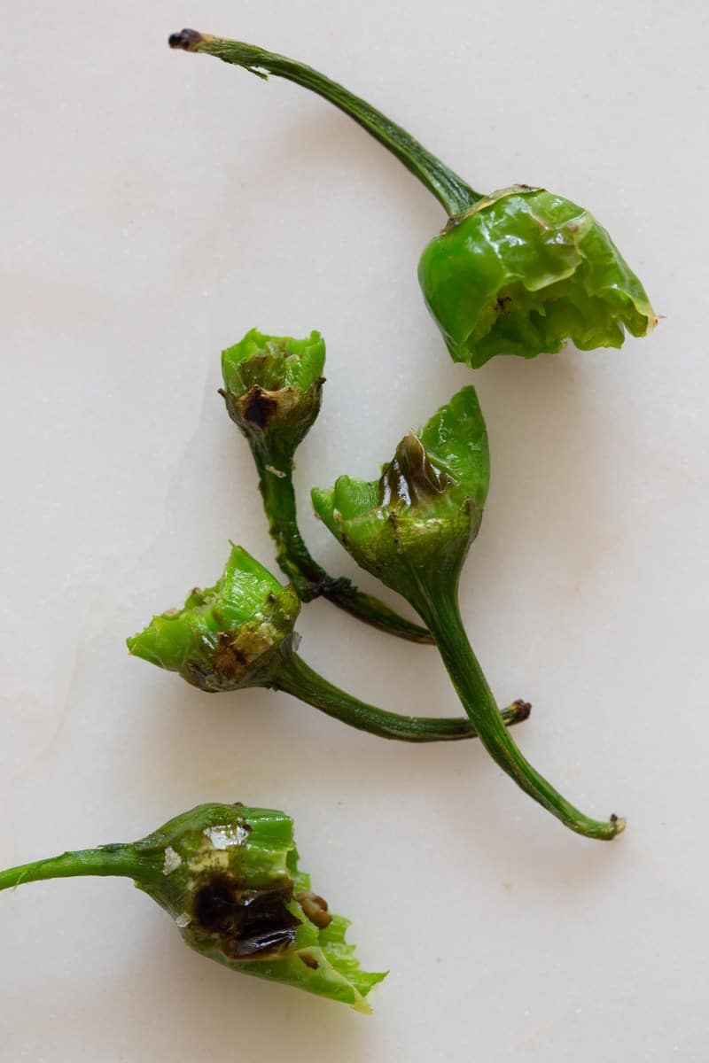 A close up of blistered shishito pepper tops and stems.