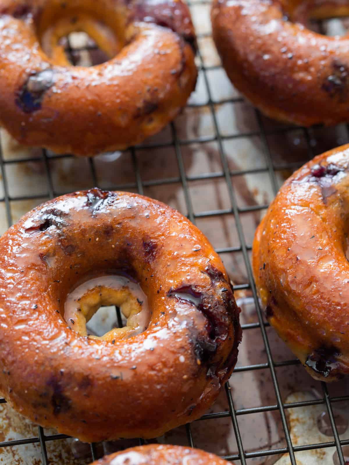Baked blueberry donuts on a baking rack.