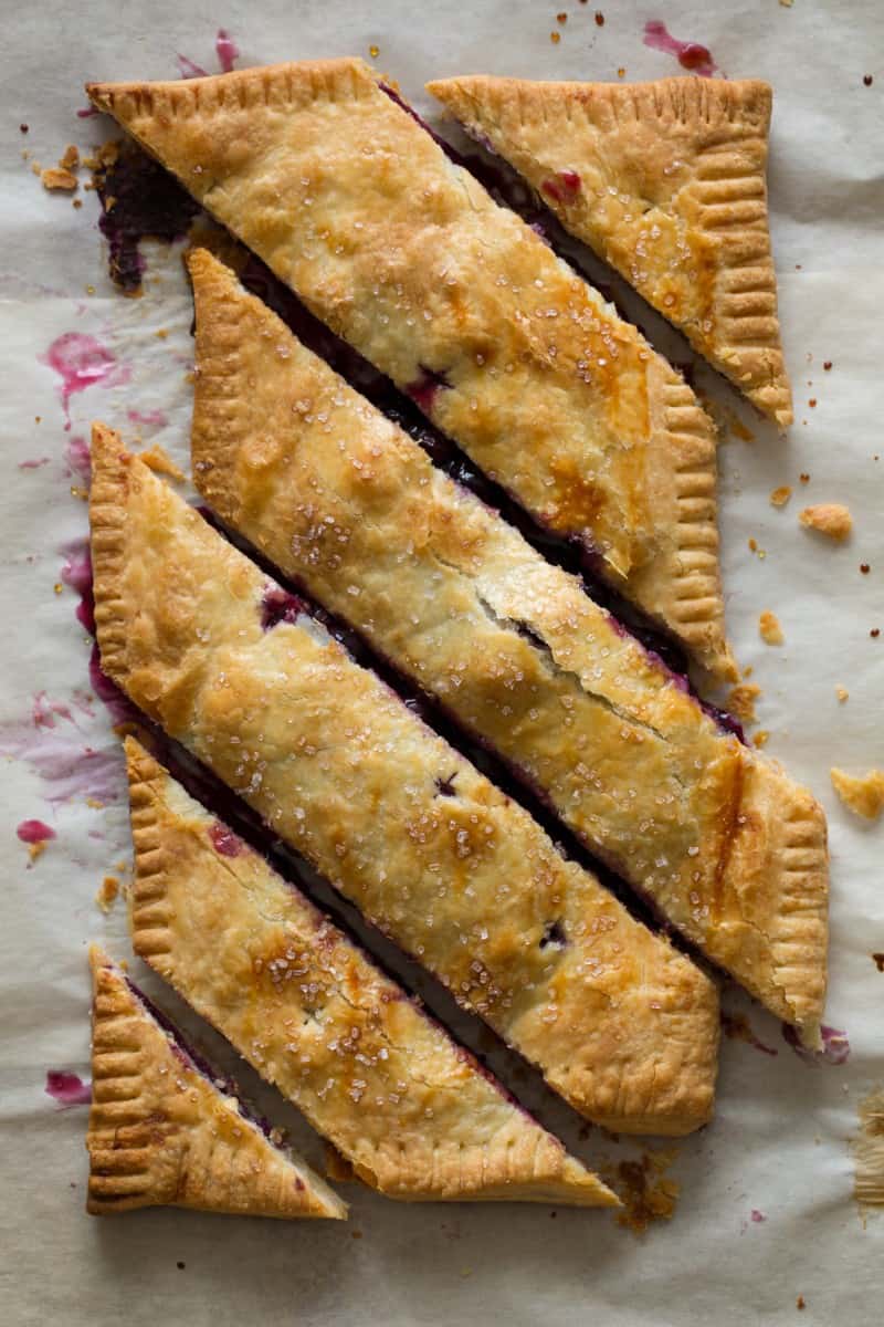 A bias cut blueberry slab pie on parchment paper.